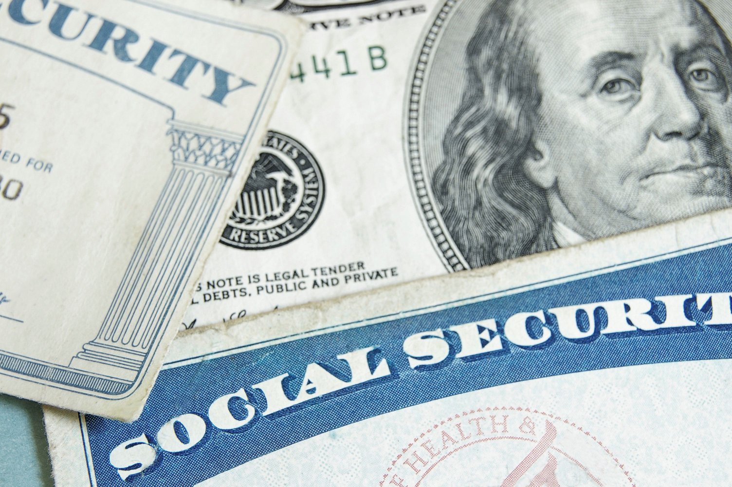 Close-up of a US $100 bill with Benjamin Franklin beside a Social Security card