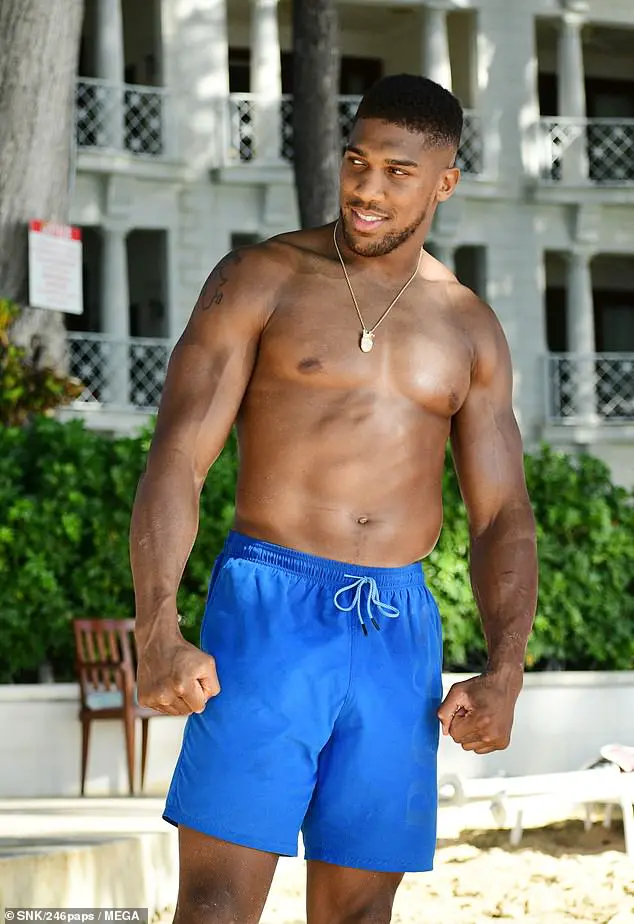 Hunk: Anthony Joshua continued to make the most of his sun-drenched getaway, as he strolled along the beach with a female companion on Thursday afternoon
