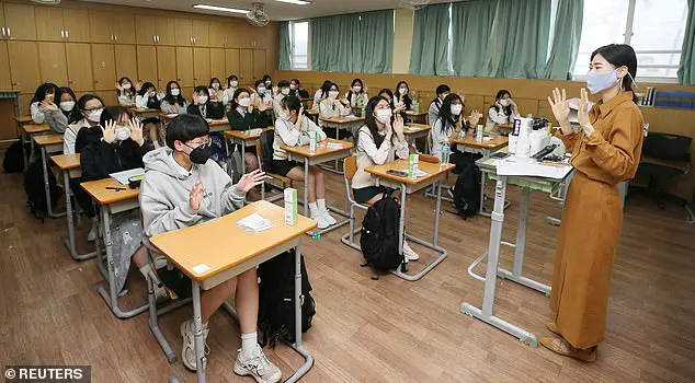 A teacher and high school students wearing protective face masks exchange greetings in a classroom as a school reopens in Cheju, South Korea, May 20, 2020