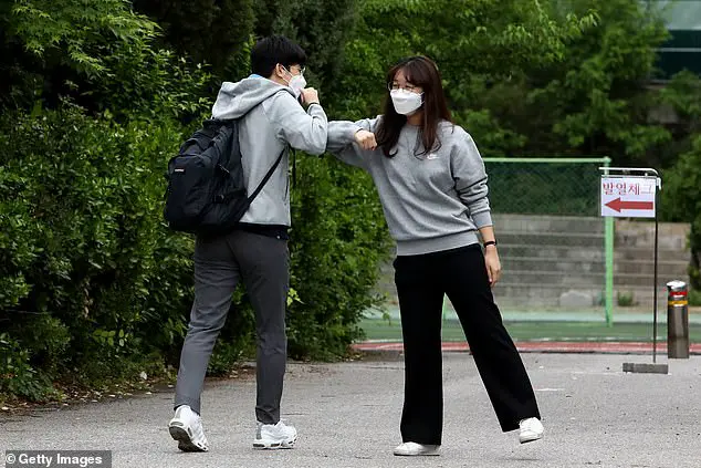 A teacher (right) welcomes a student back to school with an elbow bump at Kyungbock high school on May 20, 2020 in Seoul, South Korea