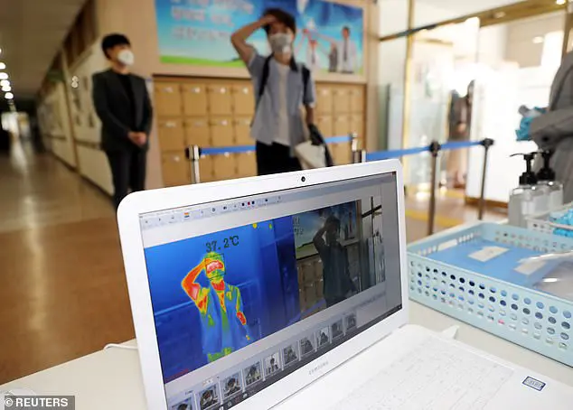 A students gets his temperature checked with a thermal imaging camera as a high school reopens in Chungju, South Korea, May 20, 2020