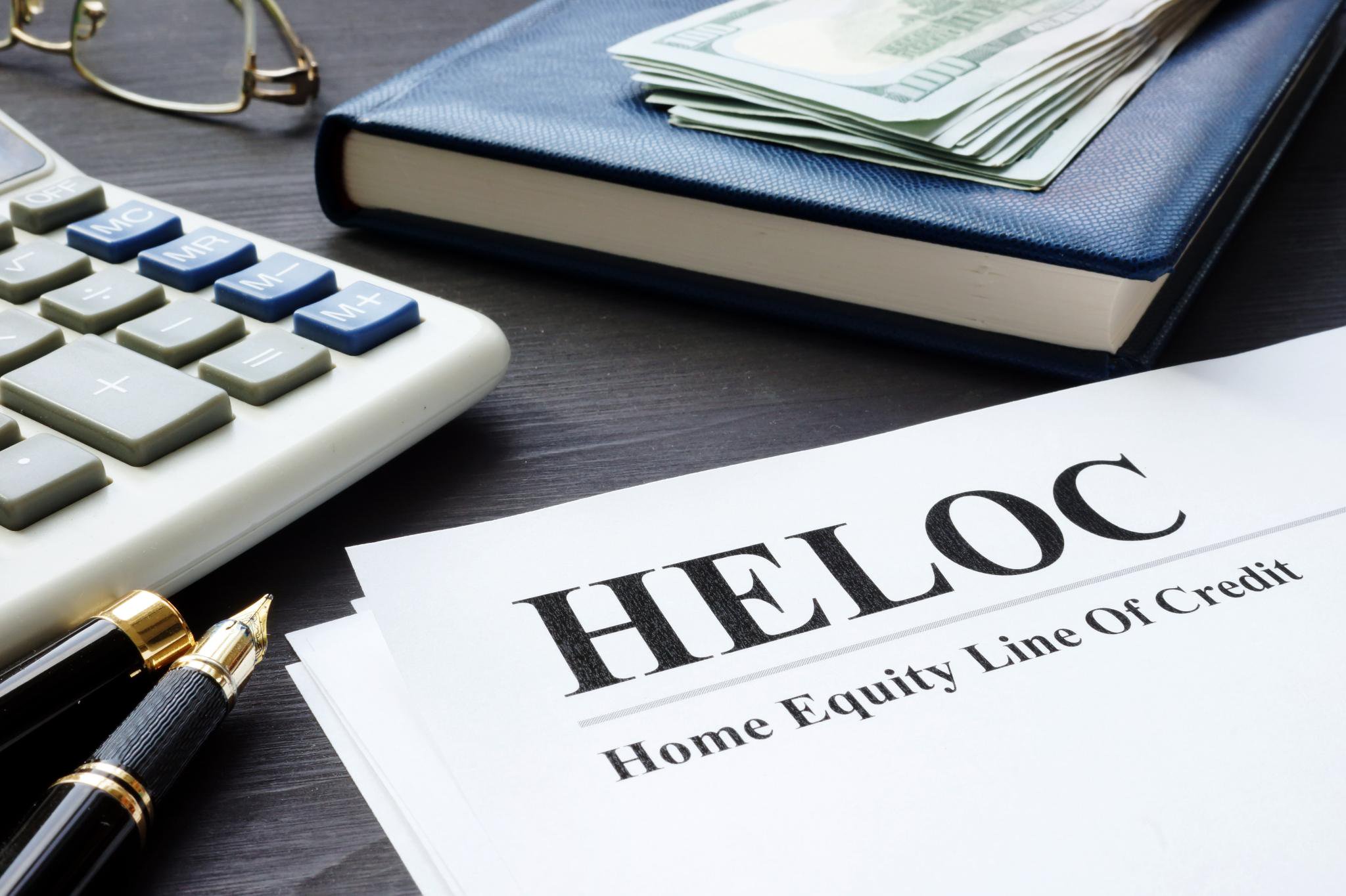 Home Equity Line Of Credit (HELOC) documents next to a calculator and cash.