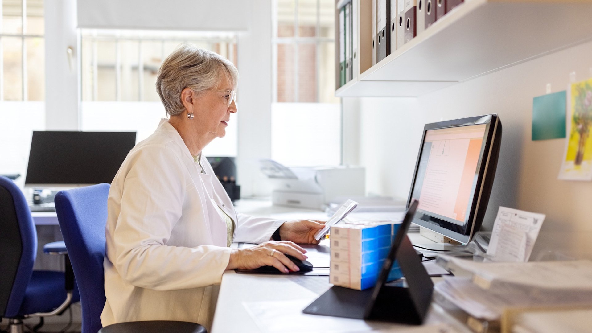 Discover a senior businesswoman sitting at her desk searching in the database, reviewing work