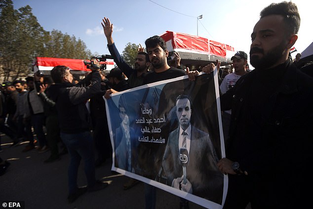 Mourners carry coffins during the funeral for the two assassinated Iraqi journalists in Basra, southern Iraq on Saturday