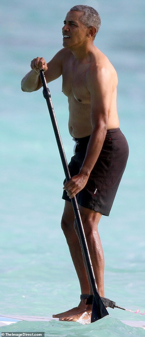 Shirtless Barack Obama shows off his fit physique during a paddle board session while on vacation in Hawaii (Photos)