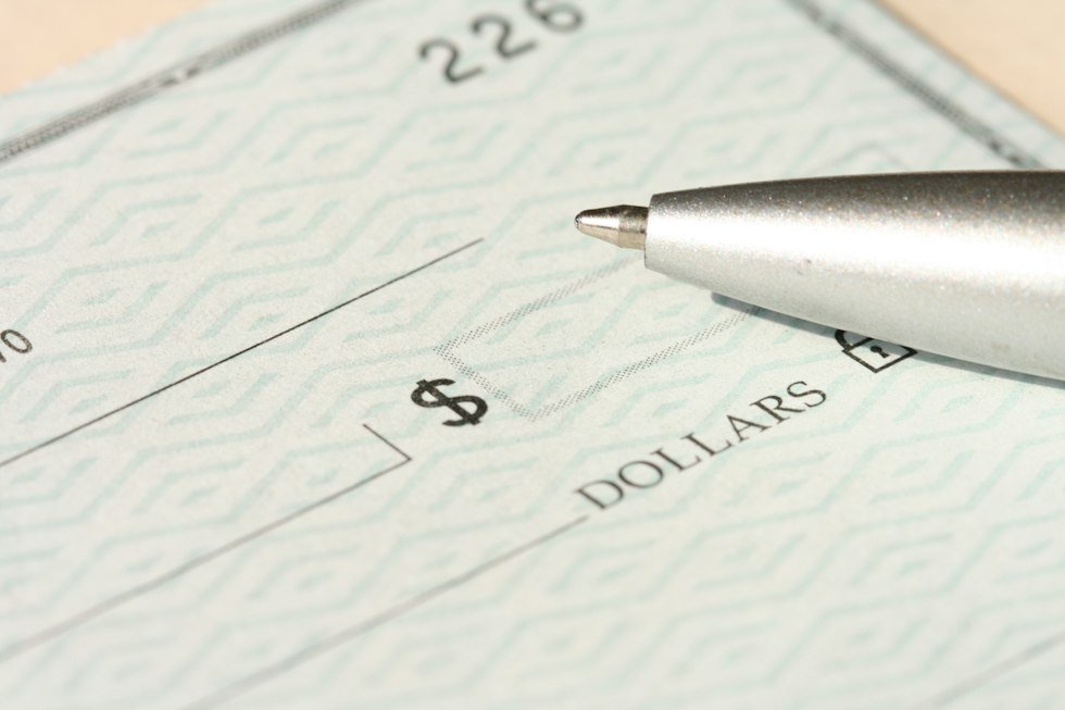 A pen rests on a check near the dollars line