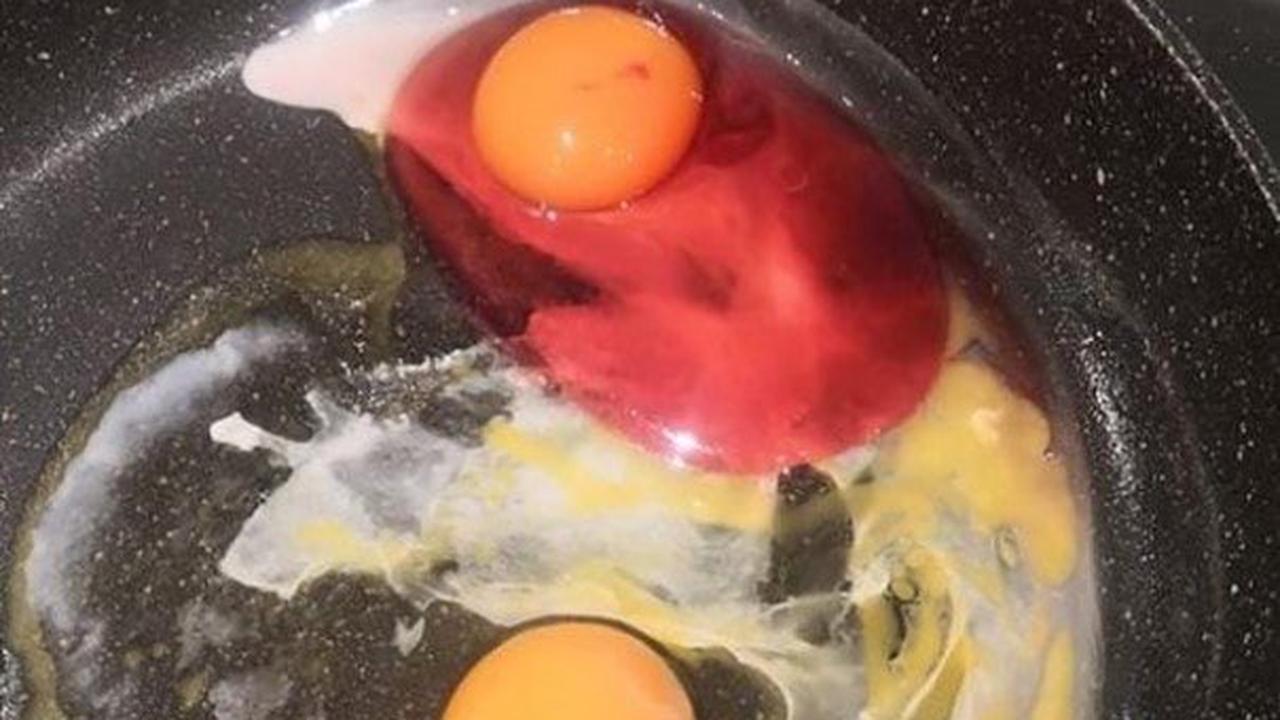 Farbenfrohes Abendessen - Frau haut pinkes Ei in die Pfanne