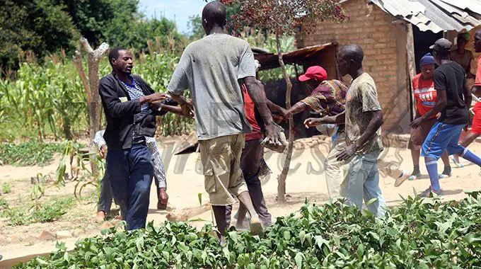 Residents of Watervlei Farm in Chitungwiza charge towards the Messenger of Court staff as they resist eviction from their dwellings yesterday. – Picture: Believe Nyakudjara