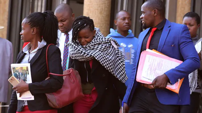 Detectives escort former Zimbabwe’s Honorary Consular for Investment and Trade in the United Arab Emirates Shamiso Fred (centre) at Harare Magistrates Courts yesterday. — Picture by Lee Maidza