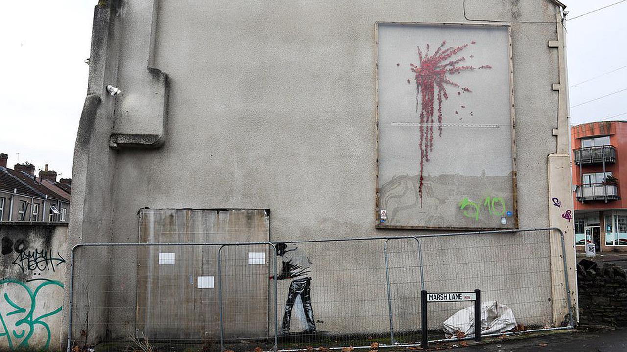Has Banksy returned to scene of the crime? NEW graffiti appears on wall showing man using crowbar to pry open cover hiding existing artwork... but mysterious tag 'Pouchy' leaves some in doubt it was really him