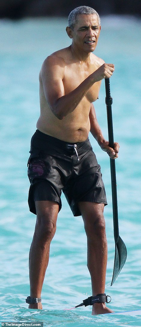 Shirtless Barack Obama shows off his fit physique during a paddle board session while on vacation in Hawaii (Photos)