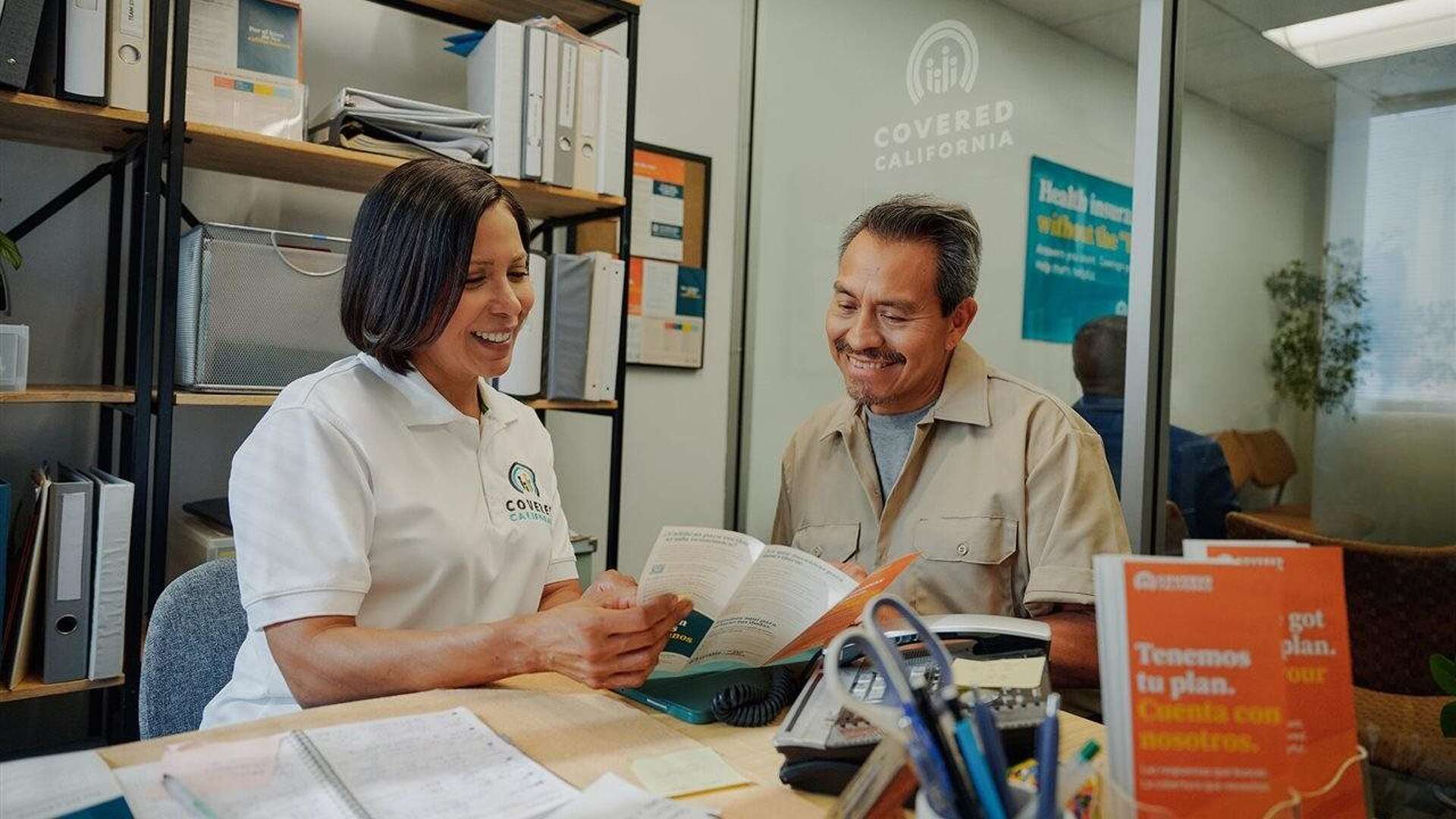 Woman helping a man with open enrollment. Covered California — open enrollment begins November 1 and ends January 31.