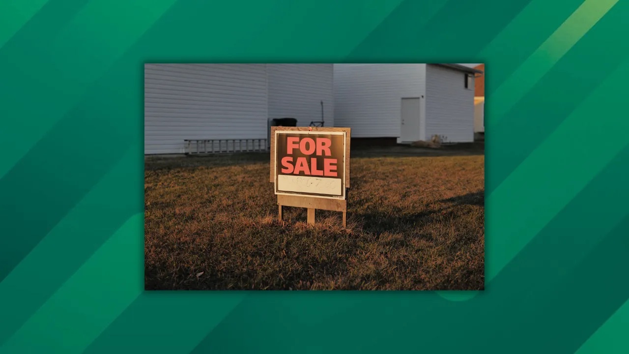 Close-up of a 'For Sale' sign in a suburban yard, indicating a property for sale.