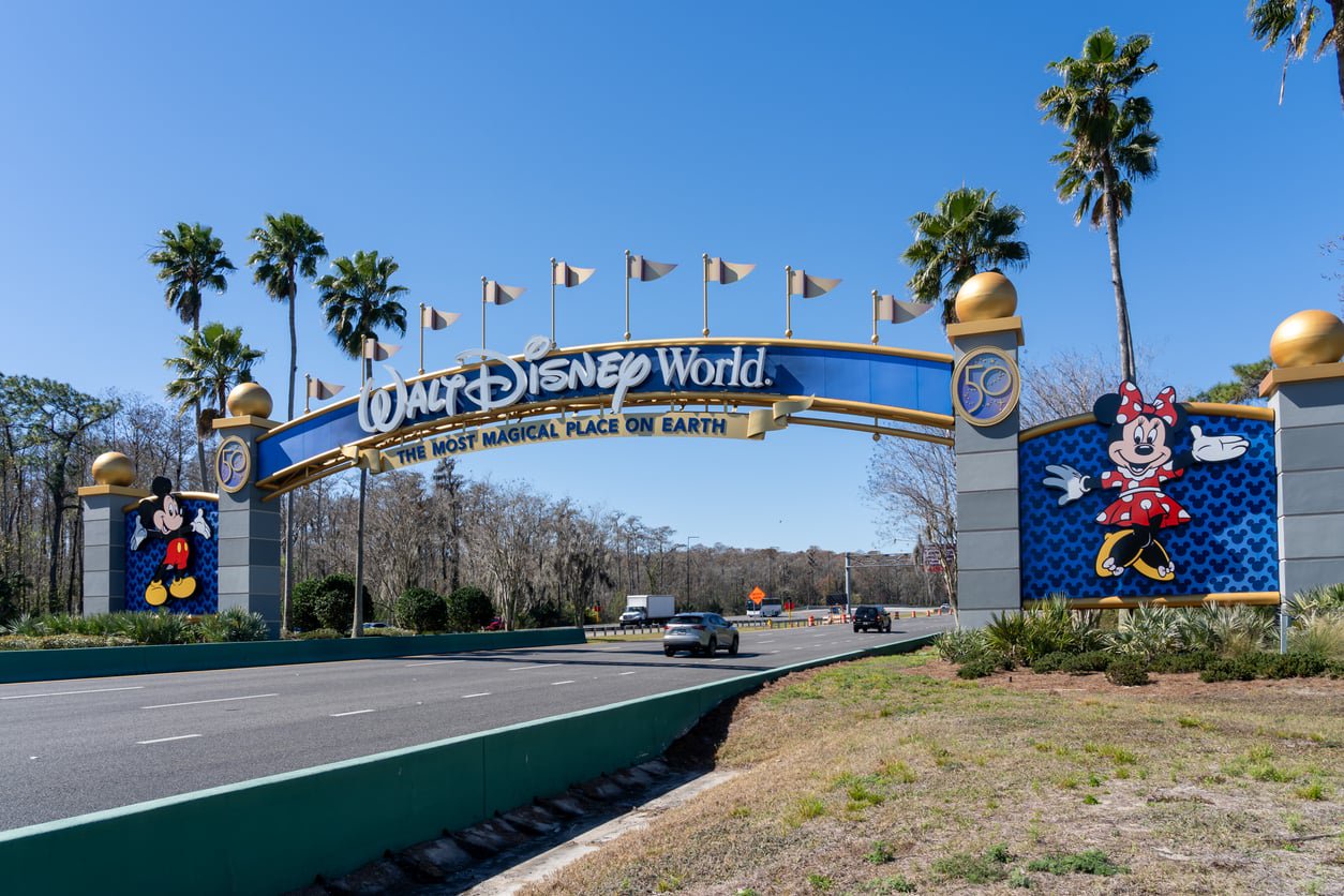 The Walt Disney World entrance archway featuring Mickey and Minnie Mouse over a multi-lane road.