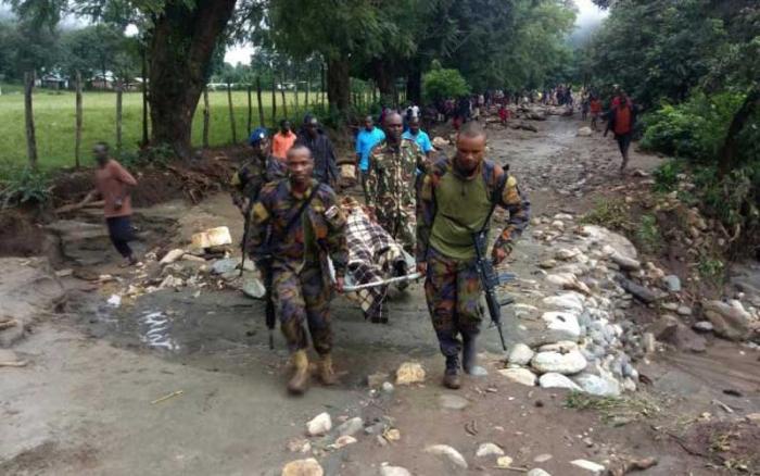 Administration policemen carry a recovered body after landslides hit two villages in West Pokot County on November 23
