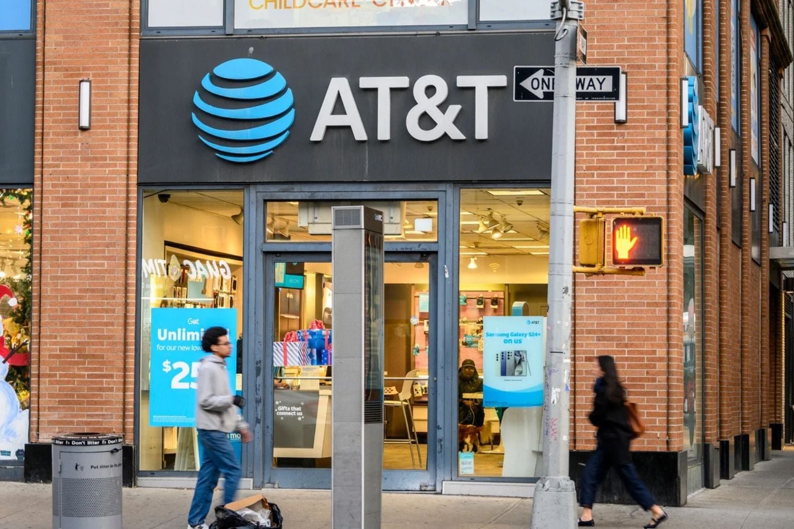 AT&T retail store exterior with the company's blue logo and pedestrians walking past the entrance.
