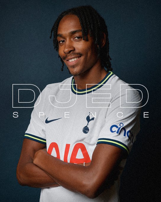 Djed Spence smiles against a Spurs blue backdrop