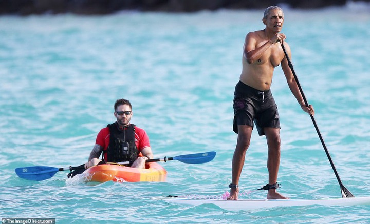 Shirtless Barack Obama shows off his fit physique during a paddle board session while on vacation in Hawaii (Photos)