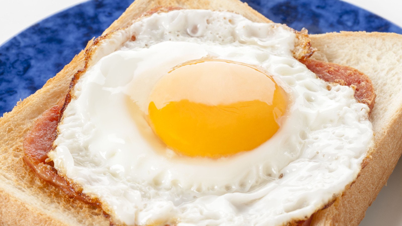 close up of a fried egg over toast on a blue plate