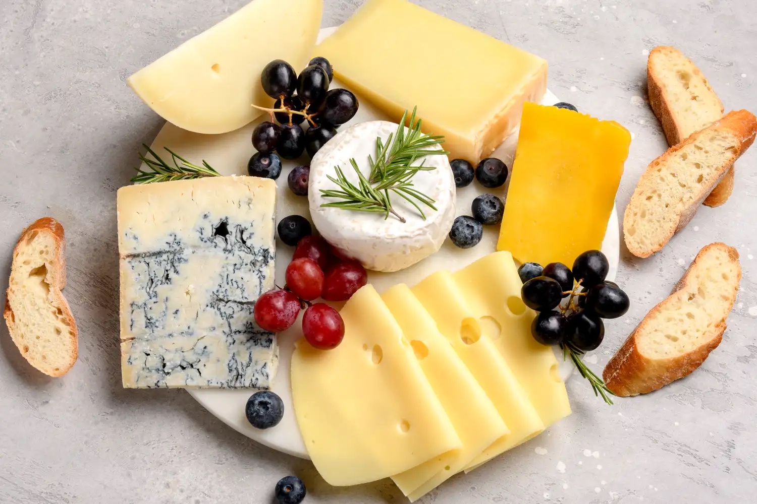 Cheese assortment platter with bread grapes and blueberries