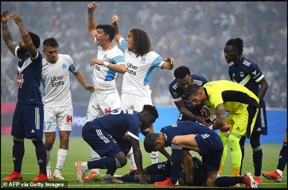 Bordeaux and Marseille players form a human shield around Samuel Kalu after the Super Eagles star collapsed on the pitch