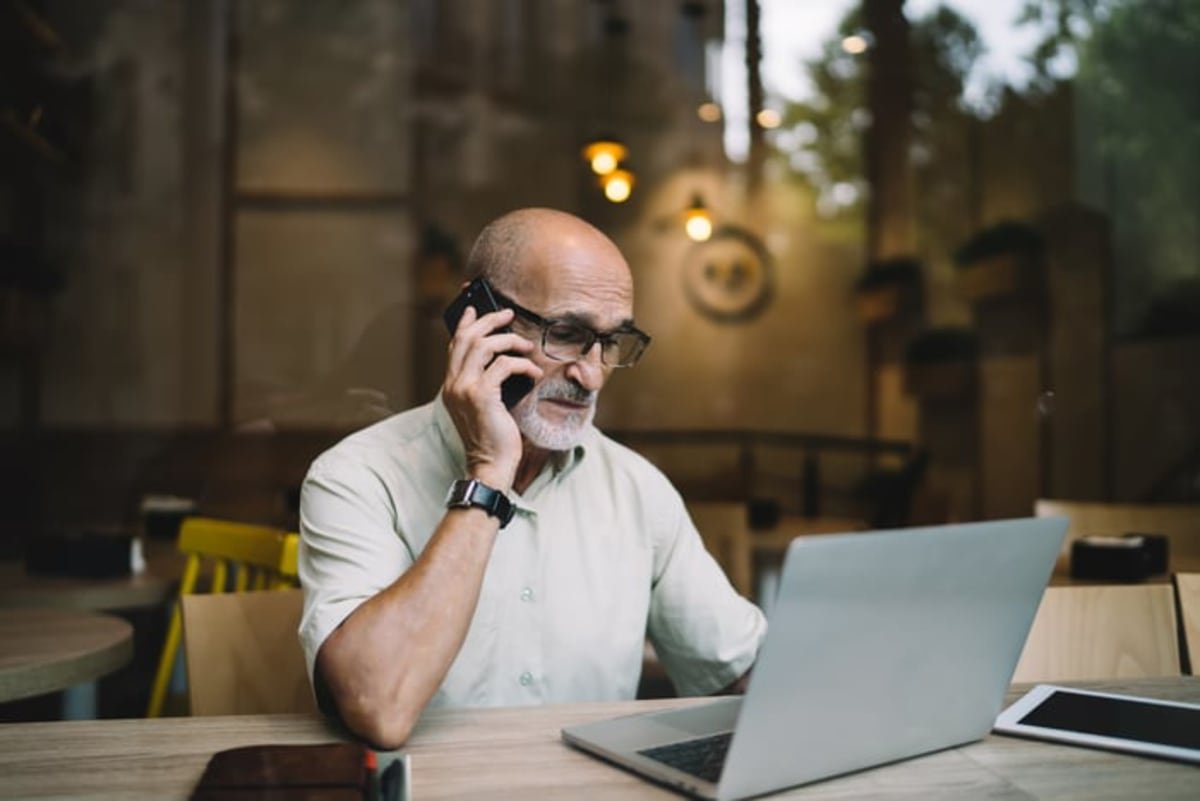 Disappointed person looking at laptop and talking on phone.