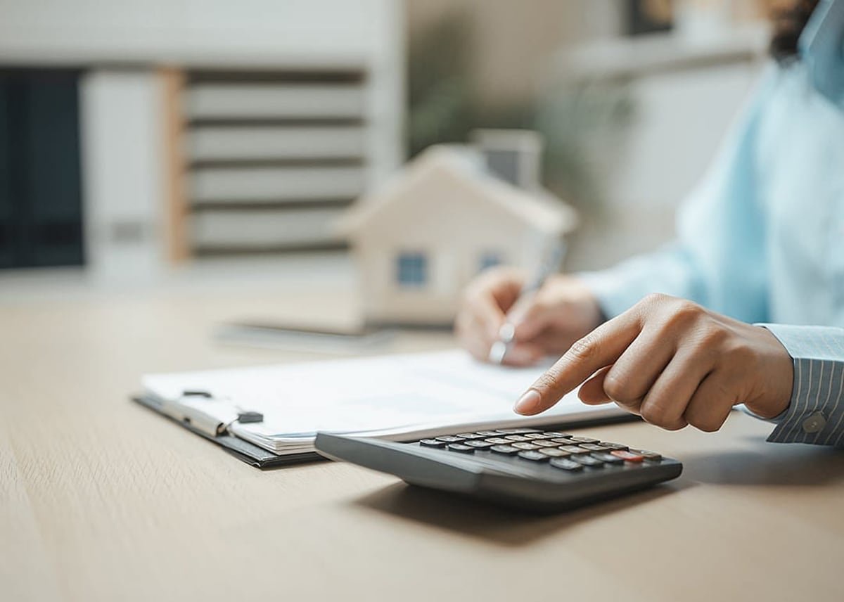 A property professional working on a document and using a calculator. - Garun .Prdt // Shutterstock