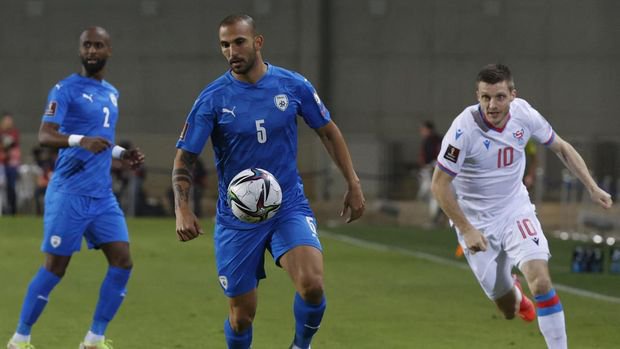 Israel's defender Orel Dgani (C) is marked by Faroe Islands' midfielder Solvi Vatnhamar (R) during the 2022 Qatar World Cup Asian Qualifiers football match between Israel and Faroe Islands, at the Netanya Stadium, on November 15, 2021 in the Israeli coastal city of Netanya. (Photo by JACK GUEZ / AFP)