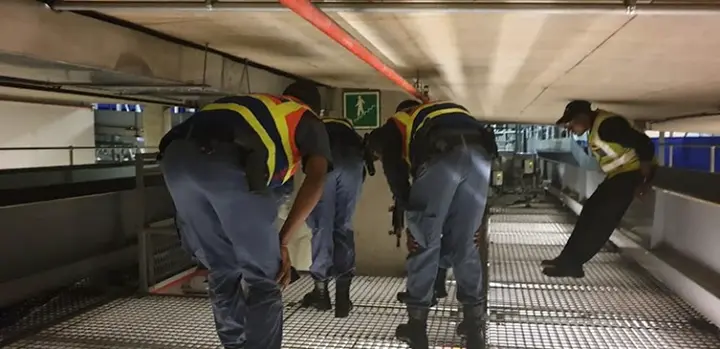 SAPS officers conducting a search between two baggage conveyor belts at OR Tambo International Airport during the festive season.