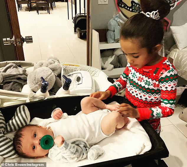 Big sister: Royalty was dressed in a Christmas sweater as she sweetly looked down at her newborn brother