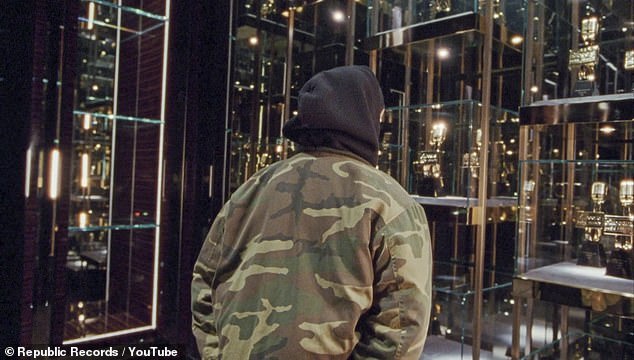 Hit maker: The rapper walks by numerous cases holding his many music awards