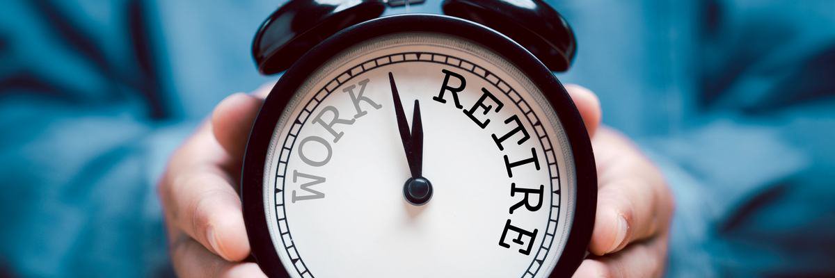 Hands hold an alarm clock with "work" on the left side and "retire" on the right.