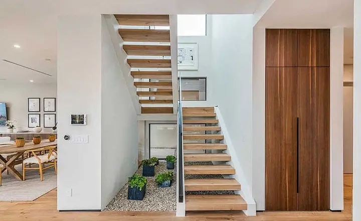 Bringing the outdoors in: Plants sit under the double staircase and walls have been painted in neutral tones