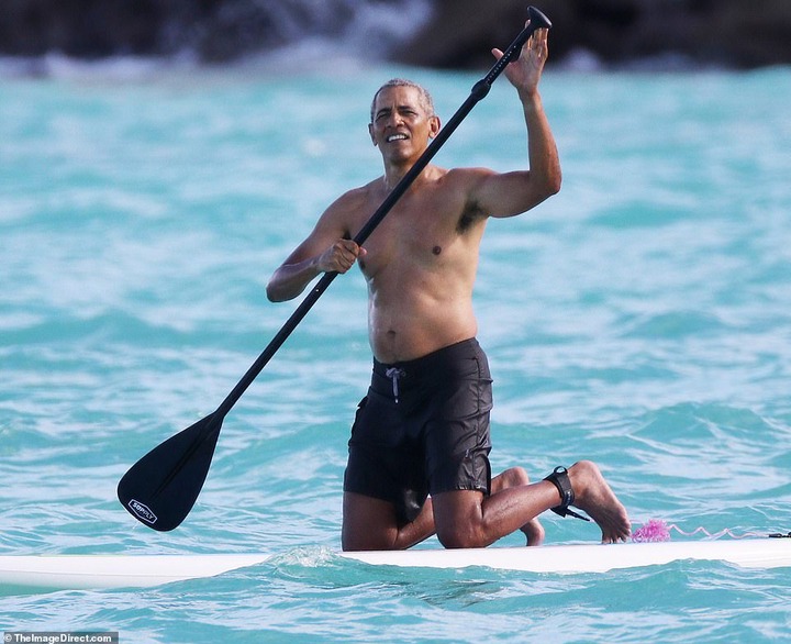 Shirtless Barack Obama shows off his fit physique during a paddle board session while on vacation in Hawaii (Photos)