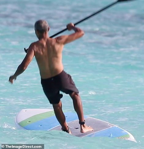 Shirtless Barack Obama shows off his fit physique during a paddle board session while on vacation in Hawaii (Photos)