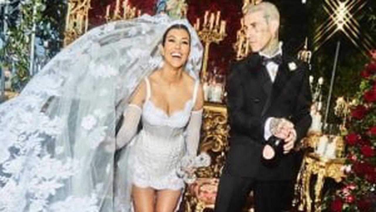 For the big day, the former 'Keeping Up with the Kardashians' star wears a Dolce and Gabbana corseted mini-dress with a long, dramatic veil, while her spouse dons a sleek black suit from the same brand.