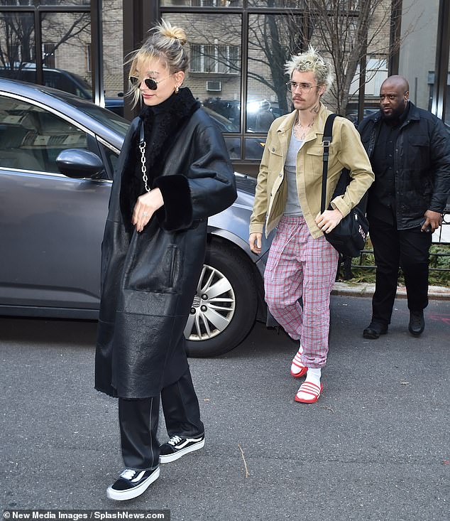 Unique approach: Bieber let a pair of red-and-grey plaid loungers rest across his hips as he crossed the street to a waiting vehicle