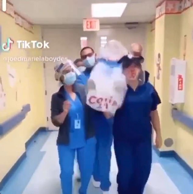 Dancing nurses carrying what appears to be a bagged corpse labelled COVID-19 (pictured) are featured in a new TikTok video which has been slammed online for being in poor taste because it appears to make fun of the coronavirus outbreak