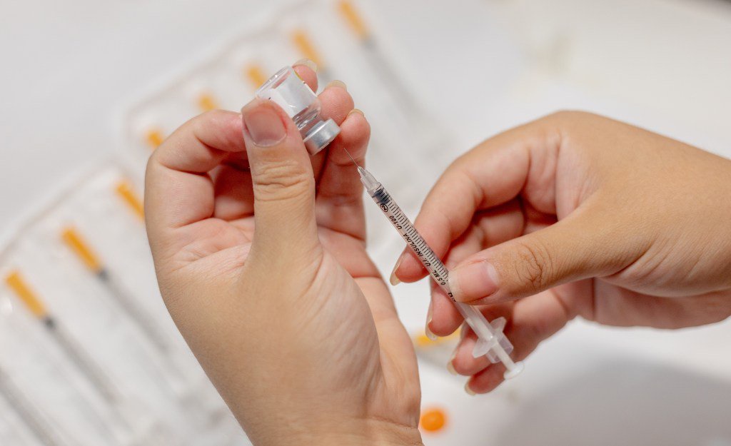 A person fills an insulin syringe from a vial of Tirzepatide medication.