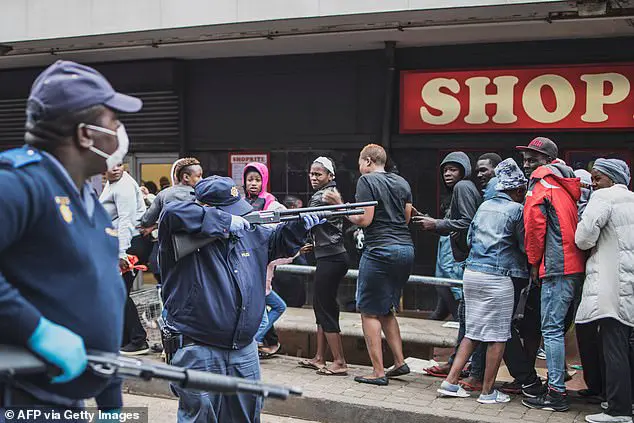 A South African policeman points his pump rifle to disperse a crowd of shoppers in Yeoville, Johannesburg,  on Sunday