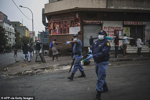 South African police officers enforce social distancing as they make shoppers stretch their arms in front of them