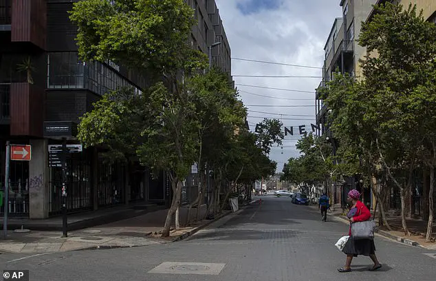 A woman crosses a nearly empty street at Maboneng precinct in Johannesburg, South Africa, Saturday