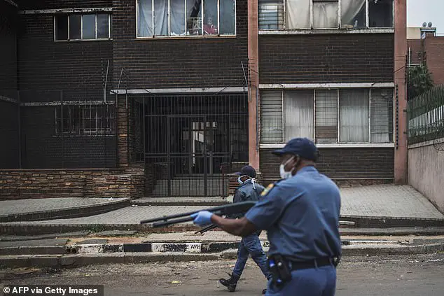 A woman observes from a window as South African policemen use pump rifles to shoot rubble bullets in an effort to disperse a crowd from a street of Hillbrow, Johannesburg, on March 28